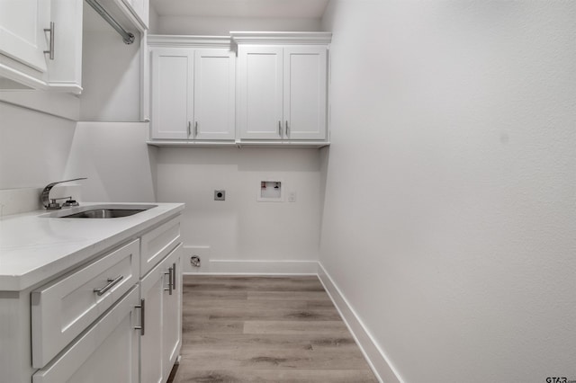 clothes washing area featuring sink, electric dryer hookup, hookup for a washing machine, cabinets, and light hardwood / wood-style floors