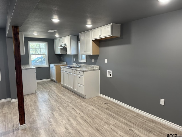 kitchen with white cabinets, light hardwood / wood-style floors, and sink