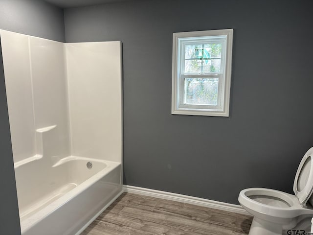 bathroom with hardwood / wood-style floors, shower / bath combination, and toilet