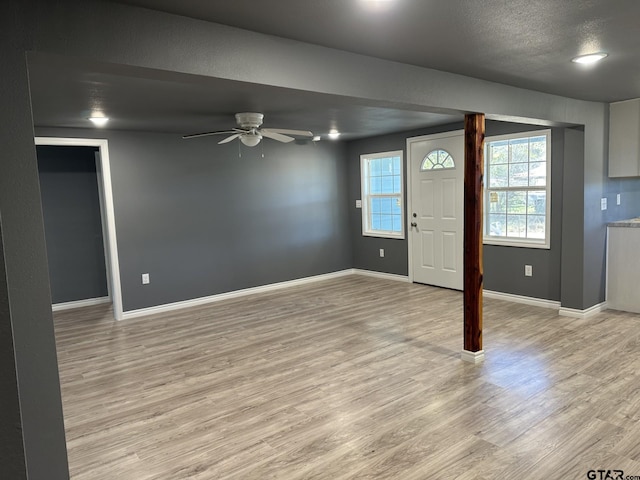 foyer featuring ceiling fan, light wood-type flooring, and a textured ceiling