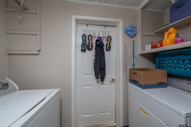 laundry area featuring wood walls and washing machine and clothes dryer