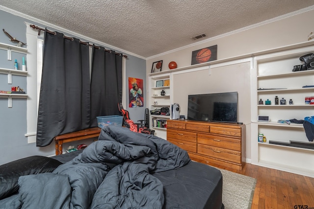 bedroom featuring wood-type flooring, ornamental molding, and a textured ceiling