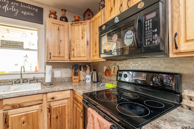 kitchen with light stone countertops, sink, black appliances, and decorative backsplash