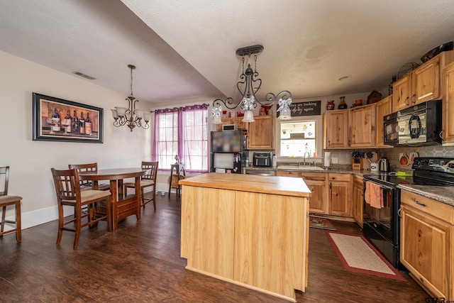 kitchen featuring black appliances, decorative light fixtures, a notable chandelier, dark hardwood / wood-style floors, and a center island