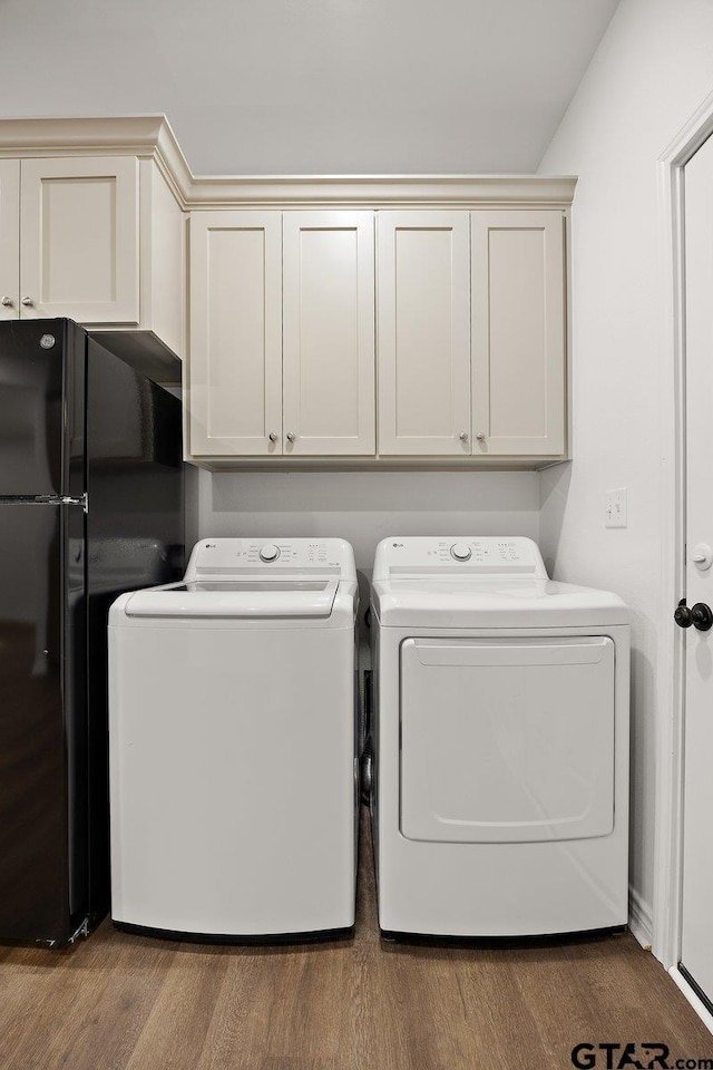 laundry area with washing machine and dryer, cabinet space, and wood finished floors