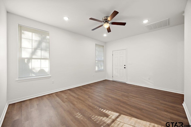 unfurnished room featuring a wealth of natural light, visible vents, dark wood finished floors, and baseboards