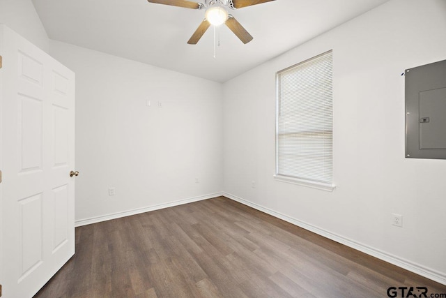 empty room featuring ceiling fan, dark wood-type flooring, electric panel, and baseboards