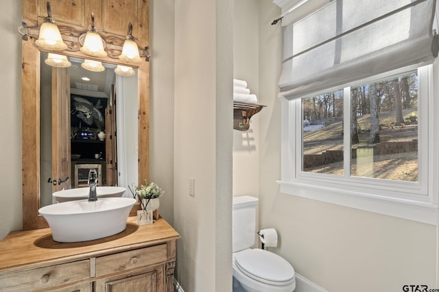 half bath featuring vanity, baseboards, visible vents, and toilet