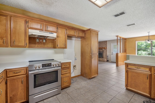 16780 Wilson Rd, Tyler, TX 75707 - kitchen with visible vents, light tile patterned flooring, under cabinet range hood, brown cabinets, and stainless steel electric range oven