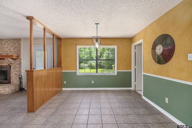 16780 Wilson Rd, Tyler, TX 75707 - unfurnished dining area with a brick fireplace, a textured ceiling, and tile patterned floors