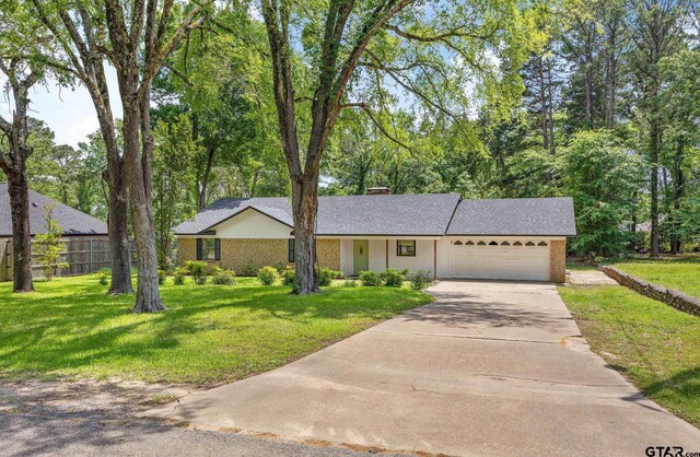 16780 Wilson Rd, Tyler, TX 75707 - ranch-style house with concrete driveway, an attached garage, fence, and a front lawn