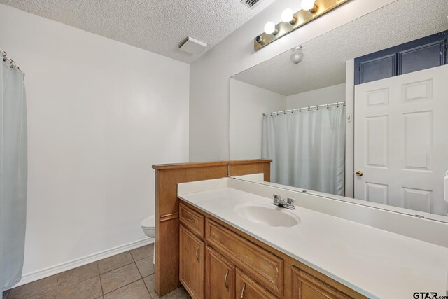 16780 Wilson Rd, Tyler, TX 75707 - bathroom with vanity, toilet, baseboards, a textured ceiling, and tile patterned floors