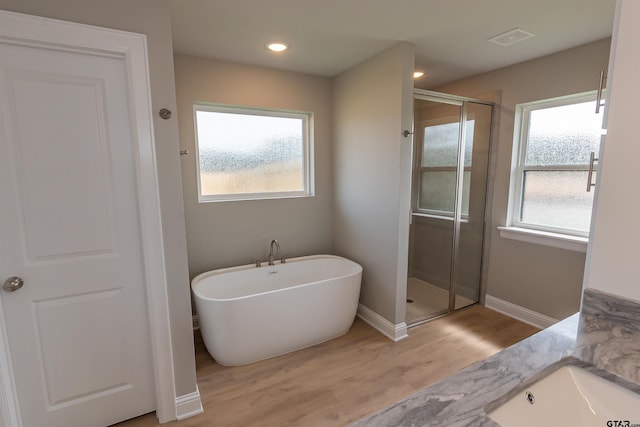 414 Bluebonnet Cir, Chandler, TX 75758 - bathroom featuring a stall shower, wood finished floors, a soaking tub, and baseboards