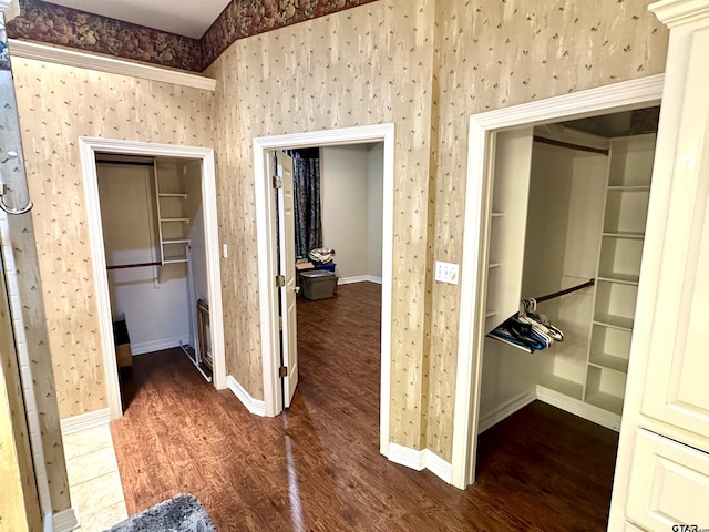 hallway featuring dark wood-style floors, baseboards, and wallpapered walls