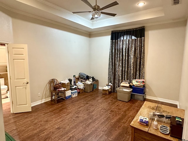 interior space featuring ceiling fan, wood finished floors, baseboards, a tray ceiling, and crown molding