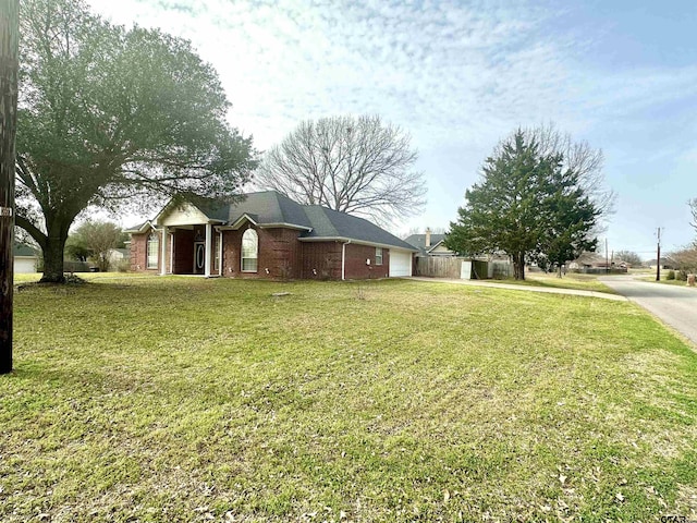 exterior space with a garage, driveway, a front yard, and brick siding