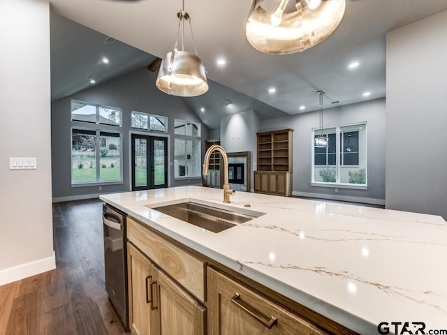 kitchen with a tiled fireplace, hanging light fixtures, sink, and dark hardwood / wood-style floors