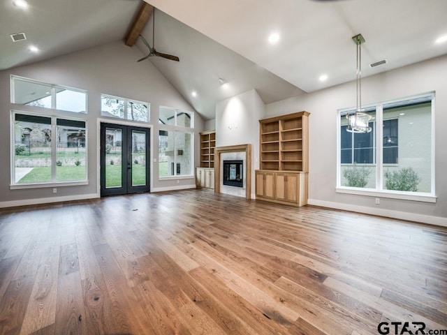 unfurnished living room featuring beamed ceiling, hardwood / wood-style flooring, and plenty of natural light