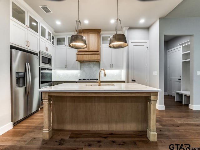 kitchen with stainless steel appliances, white cabinets, sink, a kitchen island with sink, and decorative light fixtures