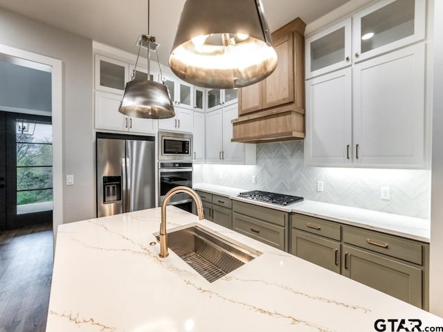 kitchen with light stone counters, sink, decorative light fixtures, and appliances with stainless steel finishes