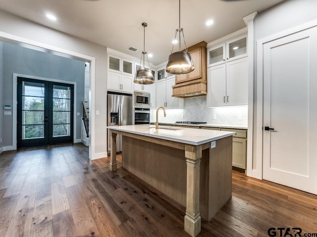 kitchen featuring sink, appliances with stainless steel finishes, decorative light fixtures, a kitchen island with sink, and white cabinets