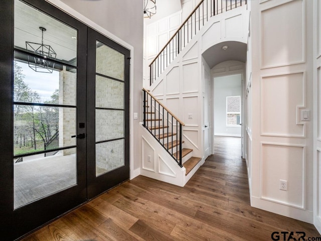 foyer entrance with hardwood / wood-style floors, an inviting chandelier, and french doors