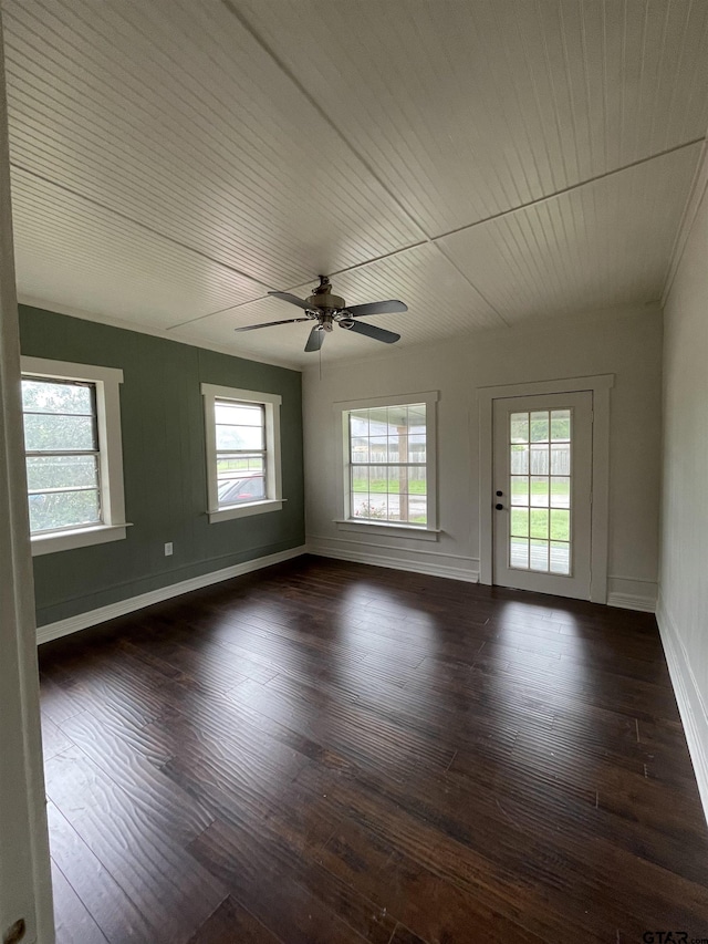 spare room with dark wood-type flooring, ceiling fan, and a healthy amount of sunlight