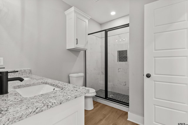 bathroom with vanity, hardwood / wood-style flooring, toilet, and a shower with shower door