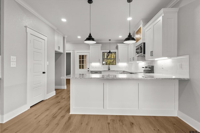 kitchen featuring kitchen peninsula, appliances with stainless steel finishes, crown molding, pendant lighting, and white cabinets