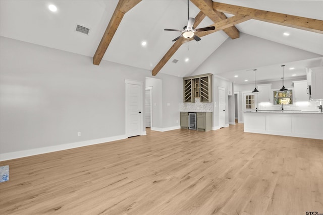 unfurnished living room with wine cooler, beamed ceiling, high vaulted ceiling, and light wood-type flooring