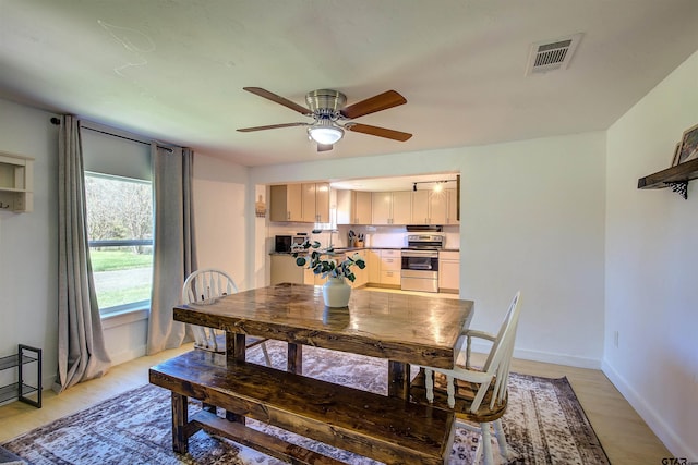 dining room with ceiling fan, light wood-type flooring, and sink