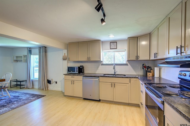 kitchen featuring track lighting, sink, light hardwood / wood-style flooring, decorative backsplash, and stainless steel appliances