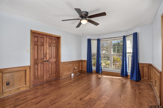 empty room featuring ceiling fan, dark hardwood / wood-style flooring, and a textured ceiling