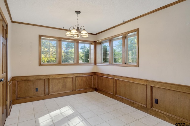 tiled spare room featuring a chandelier, a textured ceiling, and ornamental molding