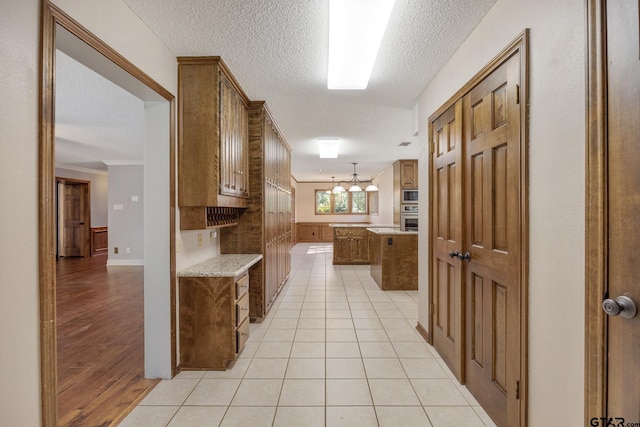 kitchen featuring a kitchen island, decorative light fixtures, a textured ceiling, light tile patterned floors, and appliances with stainless steel finishes