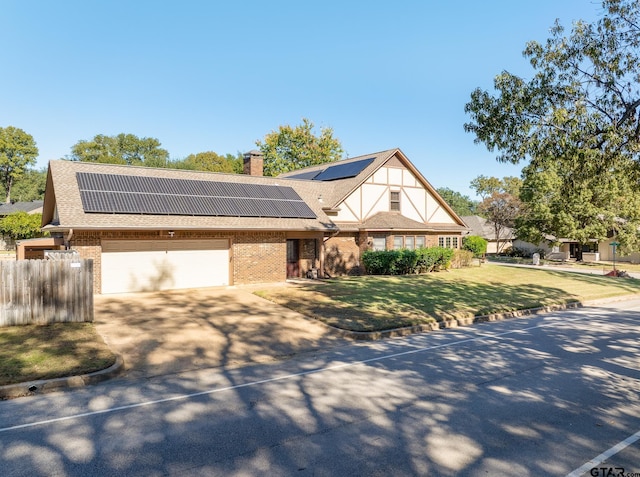 view of front of home with solar panels, a garage, and a front yard