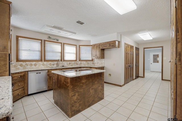 kitchen with stainless steel dishwasher, a kitchen island, light stone countertops, and a textured ceiling