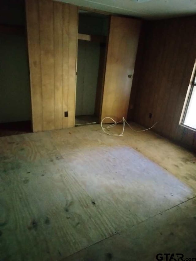 unfurnished bedroom with wooden walls and a closet