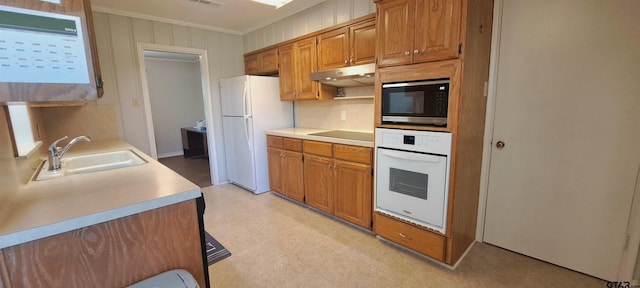 kitchen featuring white appliances, a sink, under cabinet range hood, light floors, and light countertops