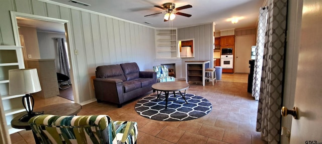 living area with crown molding, a ceiling fan, built in features, and wooden walls