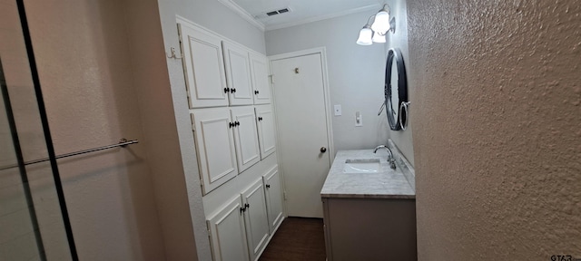 bathroom featuring ornamental molding, vanity, wood finished floors, and a textured wall