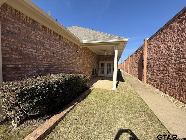 exterior space with cooling unit, ceiling fan, a patio, and a lawn