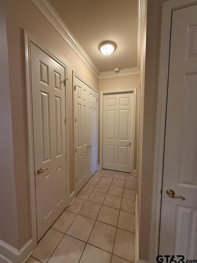 hallway with ornamental molding and light tile patterned floors