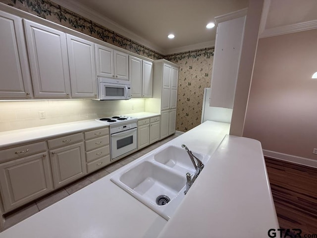 kitchen featuring oven, sink, white cabinets, and crown molding