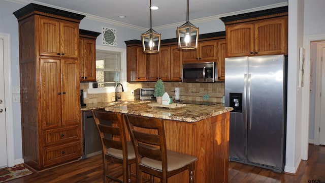 kitchen with light stone countertops, appliances with stainless steel finishes, a center island, dark hardwood / wood-style flooring, and hanging light fixtures