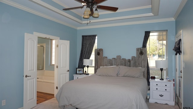 bedroom featuring ceiling fan, connected bathroom, a tray ceiling, and ornamental molding