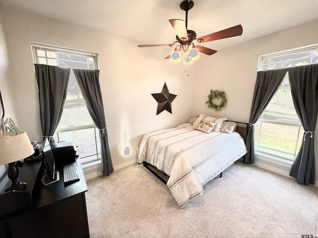 bedroom with ceiling fan, light colored carpet, and multiple windows