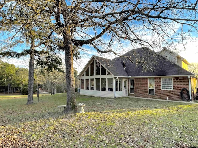 back of house featuring a sunroom and a lawn