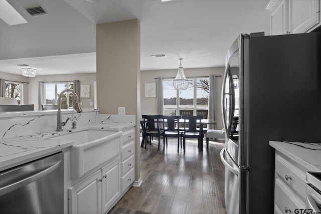 kitchen featuring visible vents, dark wood-style flooring, stainless steel appliances, white cabinetry, and a notable chandelier