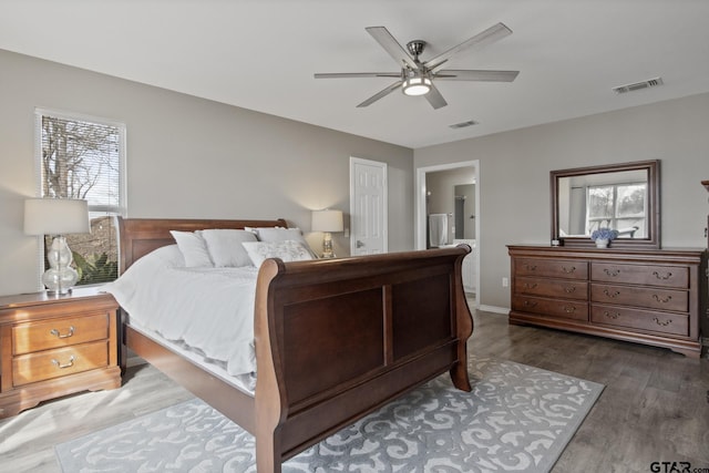 bedroom with ceiling fan, ensuite bath, wood finished floors, and visible vents